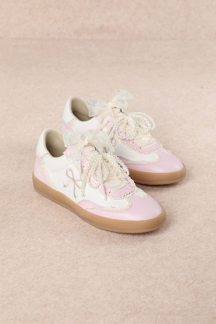 Heel Yeah Boutique Julie cream and pink sneakers with sheer ribbon laces, pearl accents, and embroidered bow motifs.